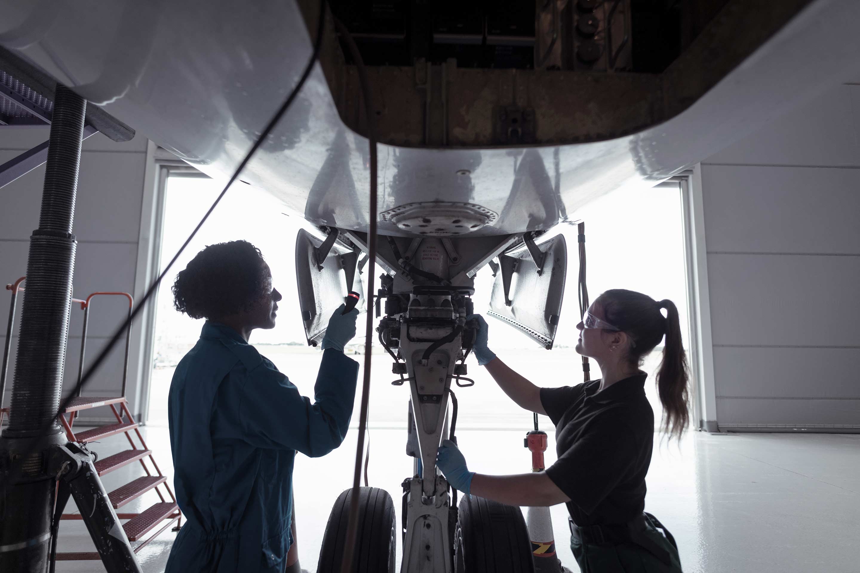 Femail echnicians conducting maintenance or pre-flight check on aircraft landing gear