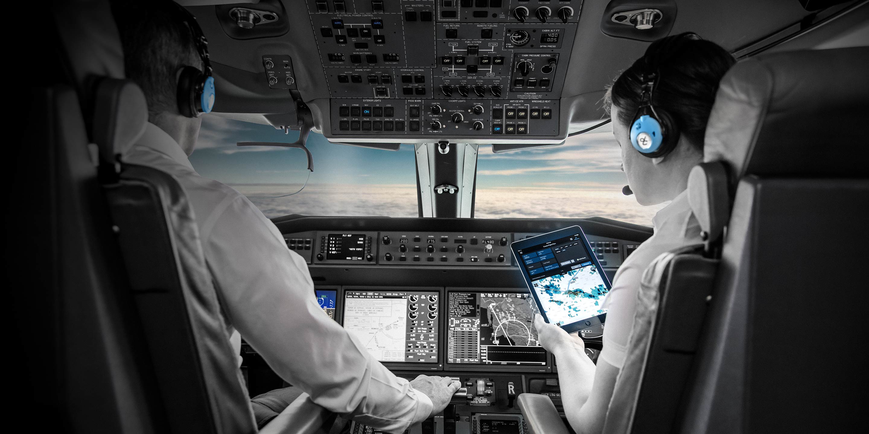 Commercial pilots monitoring avionics and flight controls inside aircraft cockpit during flight.